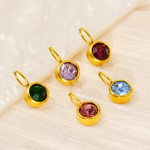 Golden stainless steel birthstone charms with colorful zircons on beige fabric texture