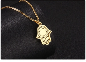 Detailed back view of golden Hamsa pendant featuring intricate honeycomb cutout design