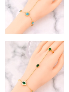 Detail of gold finger bracelet featuring blue and green zircon stones on marble background