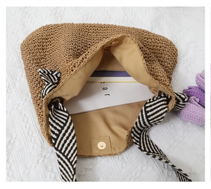 Top view of woven straw bag with beige lining, magnetic closure and striped handles