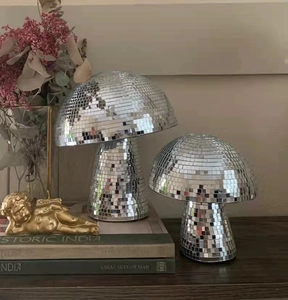 Silver mushroom disco balls in two sizes displayed on a wooden shelf with books
