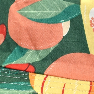 Close-up of peach and citrus fruit print fabric with detailed white double stitching