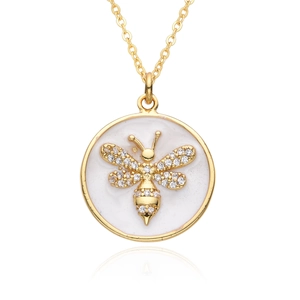 Gold bee pendant necklace with diamond wings on white enamel base, studio shot