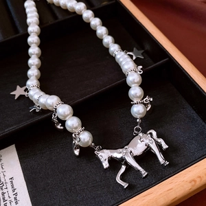 Vue macro d'un collier de perles avec un pendentif cheval en argent et breloques étoiles