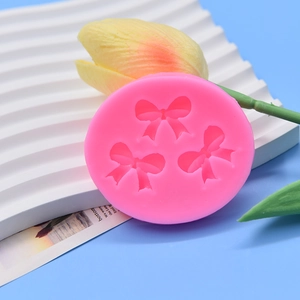 Pink silicone mold featuring three bow shapes for cake decorating and DIY crafts