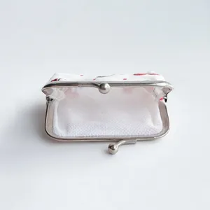 Detail view of small canvas coin purse with strawberry prints and metal clasp opening