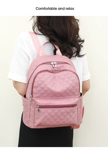 Detalle de mochila rosa acolchada con cremalleras multicapa llevada por una modelo