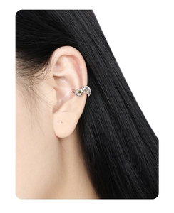 Detail of silver S925 wrap ear cuff with green gems shown on a model's ear