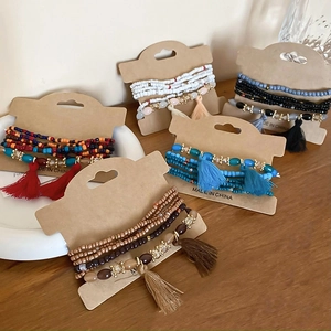 Detail of bohemian multilayer beaded bracelets with silk tassels on ceramic tray