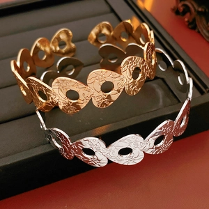 Detailed view of gold and silver hollow heart bangles with intricate floral engravings