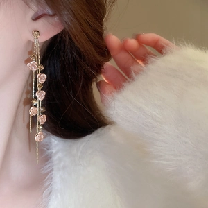 Gros plan de boucles d'oreilles pendantes dorées avec roses roses et cristaux brillants