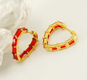 Close-up of heart-shaped gold hoop earrings with channel-set red rectangular zircon stones