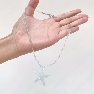Detailed shot of a light blue translucent starfish resin pendant on a beaded necklace