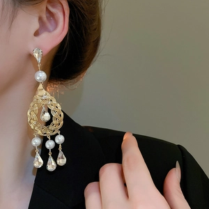 Detail of long tassel pearl earrings on model showing diamond accents and vintage gold finish