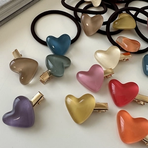 Flat lay of colorful heart-shaped acrylic hair clips and elastic ties on white background