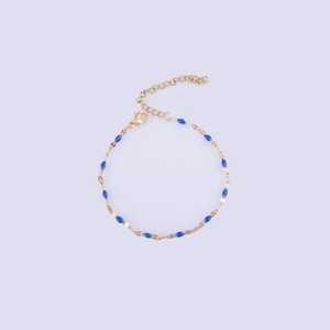 Detailed view of a gold-plated bracelet featuring deep blue enamel oval beads and lobster clasp