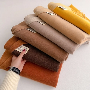 Close-up of stacked soft cashmere-like scarves in autumn colors with elegant fringe detail