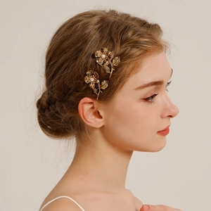 Detailed view of two gold floral hair combs with pearls on model's hair