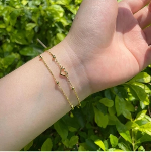 Double-layer gold heart bracelet with delicate bead chain worn on female wrist