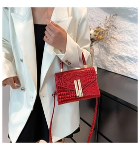 Detail of red crocodile pattern handbag with gold metal hardware and flap closure