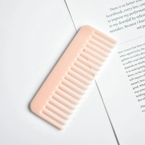 Close-up of pink marble pattern cellulose acetate wide-tooth comb on an open book