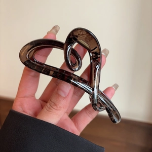 Detail of a large heart-shaped brown acetate hair claw clip for elegant hairstyles