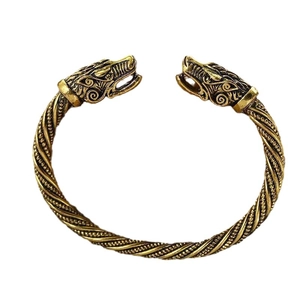 Vintage golden twisted rope bangle with detailed wolf heads on a white background
