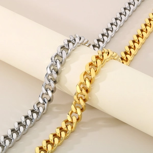 Detail of 13mm silver and gold Cuban link chains draped on a beige cylinder stand