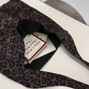 Macro view of leopard print tote bag interior capacity with books and laptop