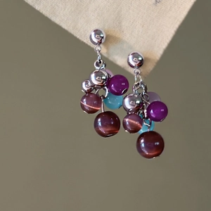 Detail of silver drop earrings with opal beads and colorful tassel chains