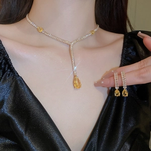 Ensemble collier et boucles d'oreilles goutte en pierre jaune avec diamants sur modèle