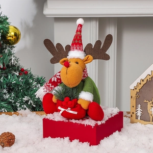 Nordic plush reindeer Christmas decoration sitting on a gift box in festive snow scene