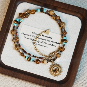 Détail d'un bracelet à plusieurs rangs en perles de pierre naturelle avec pendentif soleil
