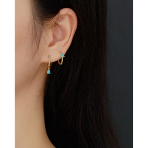 Detail of S925 silver twist hoop earrings with turquoise teardrop pendant on ear