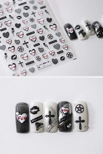 Detail view of 5D nail art stickers with black hearts, crosses and stars on white backdrop