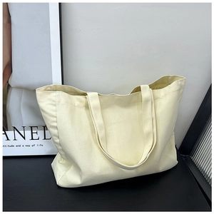 Detail shot of the large capacity canvas tote bag on a black surface in a minimalist studio