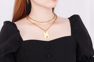 Detail view of gold double layer necklace with hollow heart rectangle pendant on model