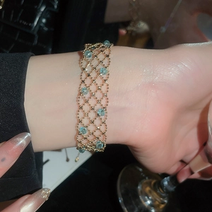 Close-up of golden mesh woven bracelet with blue crystal beads on a model's wrist