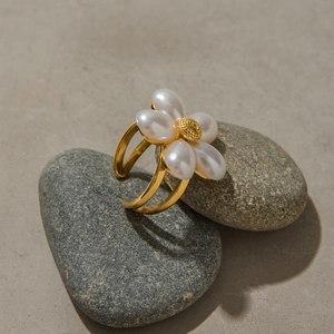 Macro view of gold flower ring with pearls on gray stones showing double band detail