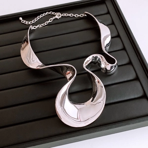 Macro detail of silver-tone chunky wrinkled necklace on black ribbed jewelry display tray
