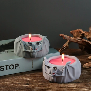 Gothic bat candle holder on wood table featuring lit pink wax candles and vintage props