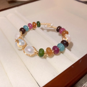 Macro detail of colorful baroque pearls and wire-wrapped beads in a beige velvet jewelry box