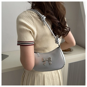 Detail showing a silver bow handbag with unique knotted shoulder strap for women