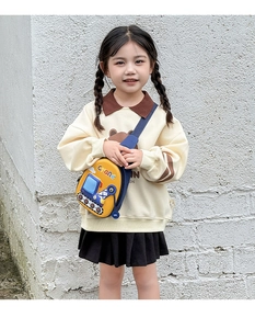 Outdoor shot of a toddler girl wearing a cute yellow crane-shaped cartoon chest bag