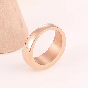 Anello minimalista in acciaio inossidabile oro rosa con superficie liscia su sfondo bianco