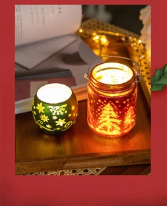 Close-up of glass Christmas candle holders with snowflake and tree patterns on wood