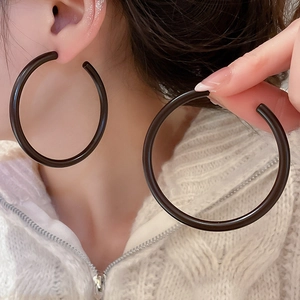 Close-up of large black C-shaped acrylic hoop earrings on model for a minimalist modern look