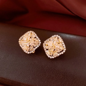 Macro shot of gold rhombus earrings with pavé zircons on premium leather surface