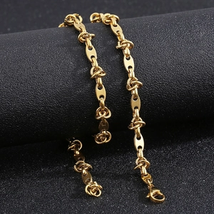 Detailed view of golden titanium steel coffee bean chain necklace on black texture