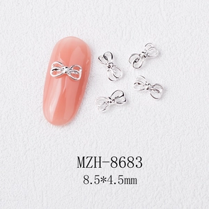 Macro detail of silver alloy bow nail charms with 8.5x4.5mm dimensions on white base